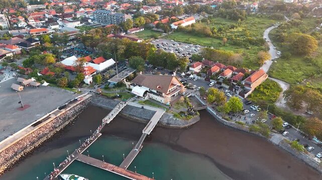 Aerial sunset view, passengers disembarking at Sanur Harbour, Bali, Indonesia, with the ferry terminal, pier, waterfront and surrounding district visible