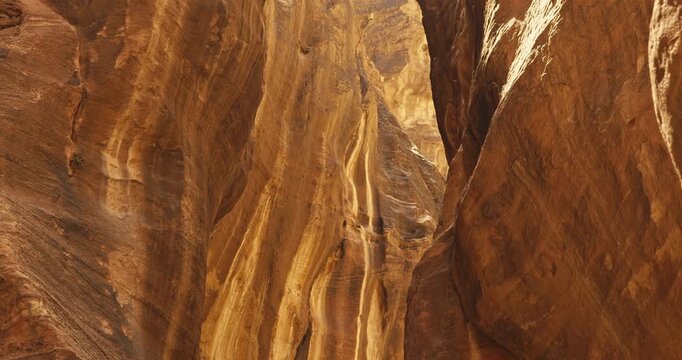 Close up of towering sandstone canyon walls in Petra, Jordan showcasing layered rock textures, rugged cliffs, and warm natural daylight.