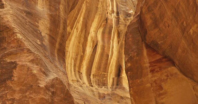 Close up of layered sandstone canyon walls in Petra, Jordan showcasing weathered rock textures, natural erosion patterns, and warm daylight.