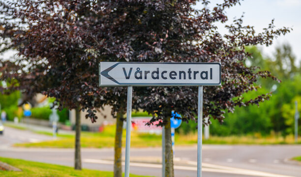 Healthcare center direction sign marked V&aring;rdcentral along quiet Swedish suburban road.