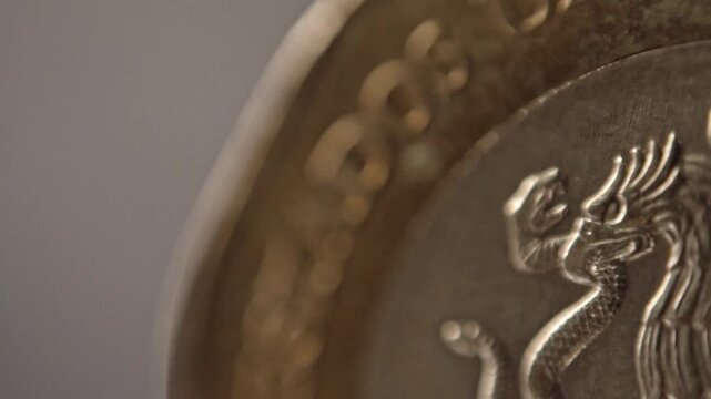 Macro close up of detailed eagle engraving on metallic coin surface. Fine raised lines, textured relief and curved patterns create an intricate abstract view of the currency design