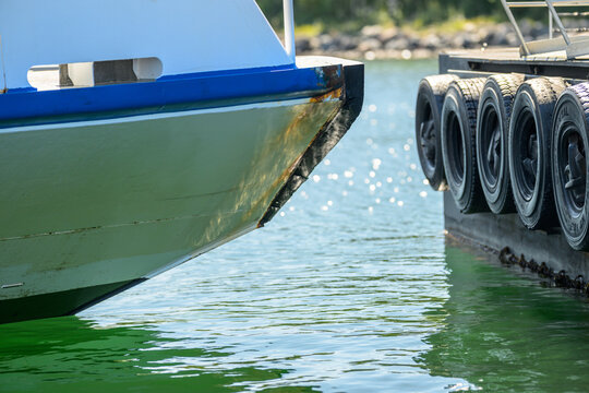 Boat bow beside tire fenders at sunny harbor dock.