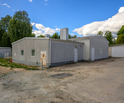 Plain gray utility building under dramatic blue summer sky.