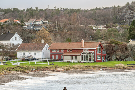 Cluster of coastal homes along shoreline with calm water and natural landscape.