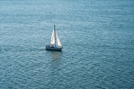 White sailboat gliding across deep blue sea.