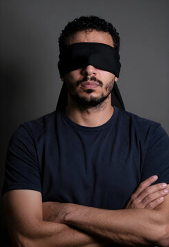 Blindfolded man with crossed arms of uncertainty ignorance injustice and lack of vision or directionless