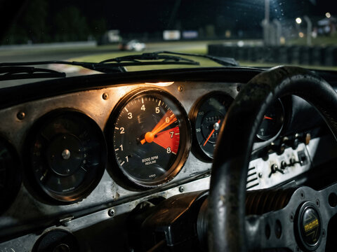 Vintage race car dashboard and tachometer during night racing
