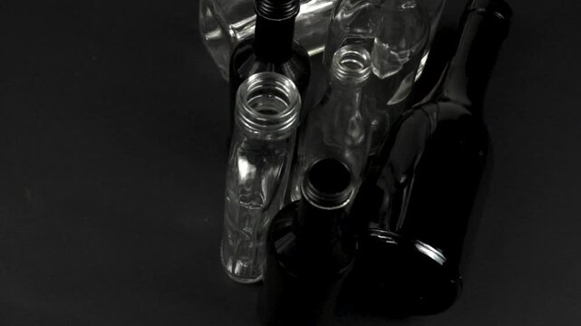 Glass bottles of various color, shapes and size stand on a black background, versatile containers used for storage of different objects and liquid. Glass bottles collection, side view
