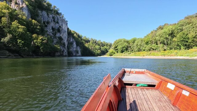Point of view shot from a traditional wooden boat navigating the scenic Danube Gorge near Kelheim, Bavaria, on a bright sunny summer day