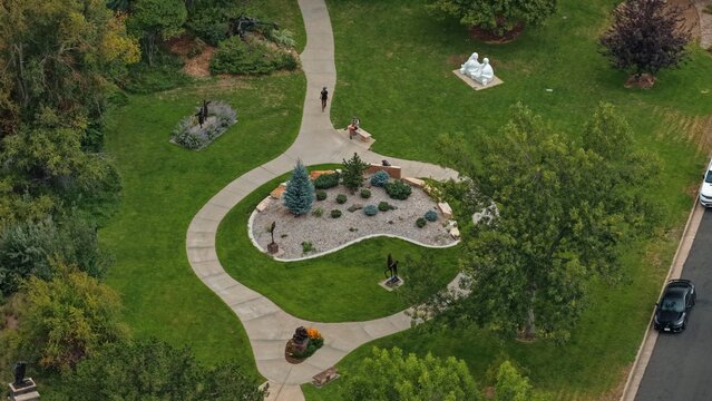 Loveland, Colorado, United States - 14 August 2026: Aerial view of Benson Sculpture Garden featuring winding concrete pathways, various bronze sculptures, manicured lawns, and lush trees.