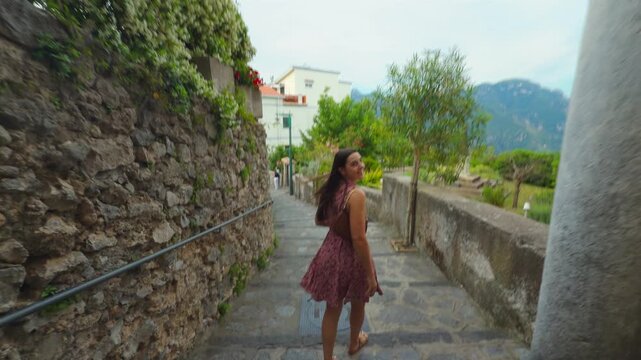 Woman Walking Down Stone Path in Mediterranean Village Overlooking Sea and Hills in Ravello Italy