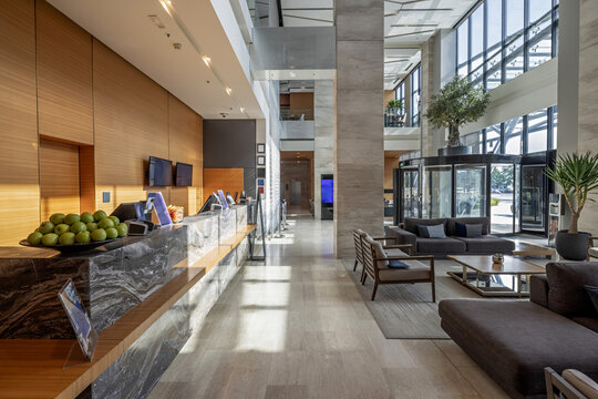 Spacious modern hotel lobby featuring a marble reception desk and comfortable lounge seating