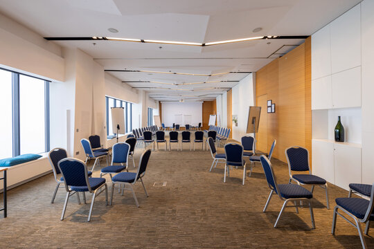 Spacious contemporary conference hall with blue chairs arranged for interactive team workshop