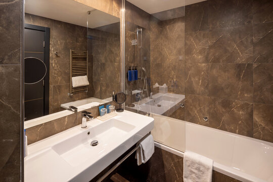 Modern luxury hotel bathroom featuring marble wall tiles glass shower partition and white sink