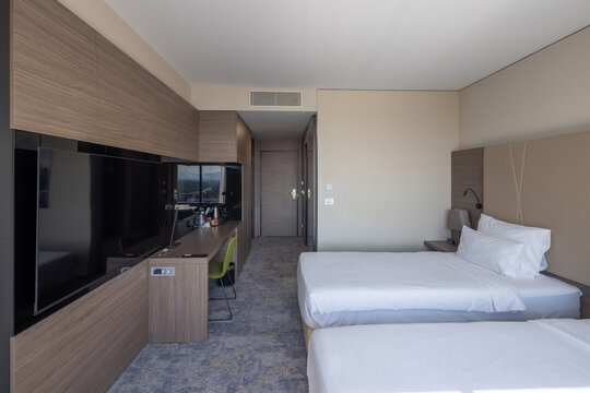 Contemporary twin hotel room with wooden wall panels television unit and comfortable beds