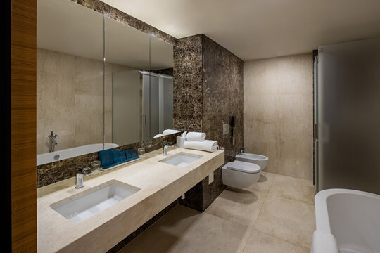 Spacious luxury hotel bathroom with marble walls double vanity sinks and bathtub