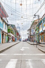 Fototapeta premium Colorful colonial street with hanging decorations in Filandia, Colombia