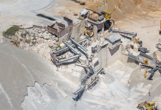 Aerial view of a stone quarry with crushing machinery, conveyor belts, and piles of gravel in Struga, Municipality of Strug, North Macedonia.