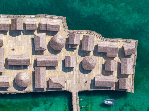 Aerial view of The Bay of Bones Museum, a reconstructed pile dwelling settlement with thatched-roof huts on a wooden platform in Peshtani, Municipality of Ohrid, North Macedonia.