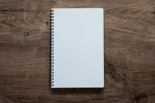 Photo mockup of blank empty white sheet notebook on wooden background.