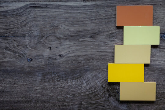 Birds eye view photo of dark wood background with negative space and yellow brown five tiles to the right. 