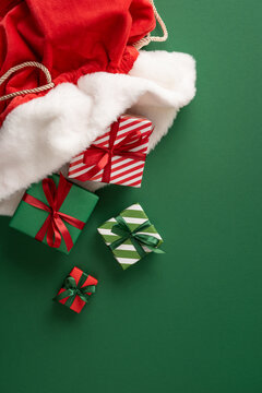 Merry Christmas gifts from Santa Claus spilling from a red velvet sack with wrapped presents and ribbons on vertical green background