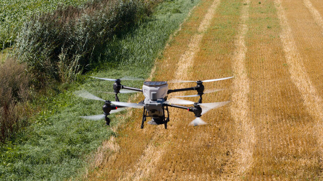 Aerial view of an agricultural drone flying over a field with harvested crops and green vegetation in Onstwedde, Groningen, Netherlands.
