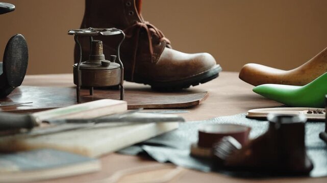 Leather boot beside shoe lasts a brass burner and hand tools on a cobbler workbench