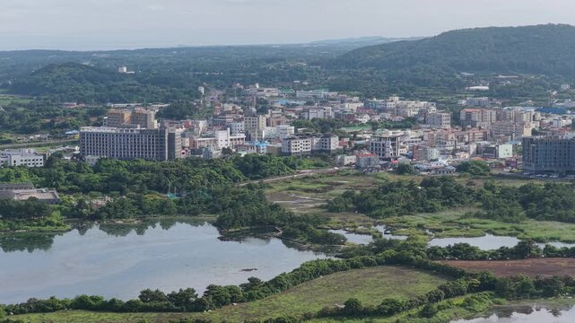 Urban Cityscape Near Lush Green Ojo-ri Wetland Protection Area In Ojo-ri, Seongsan-eup, Seogwipo-si, Jeju-do, South Korea. - aerial shot