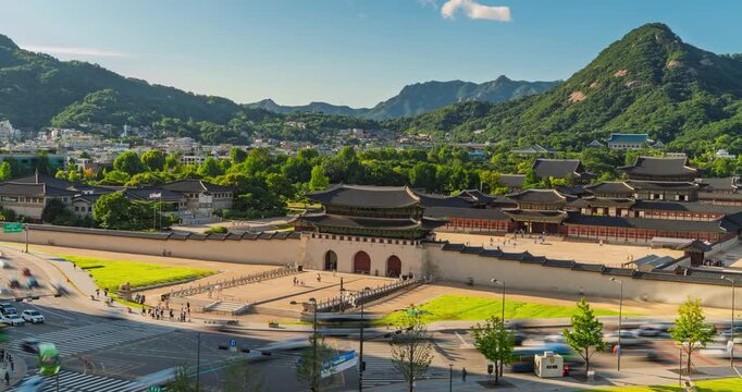 Aerial motion lapse pans left to right across Gyeongbokgung Palace in Seoul, South Korea revealing fast moving traffic and forested Bugaksan mountain behind