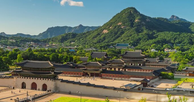 Timelapse shows tourists strolling through Gyeongbokgung Palace grounds in Seoul, South Korea beneath towering Bugaksan mountain on a clear summer day