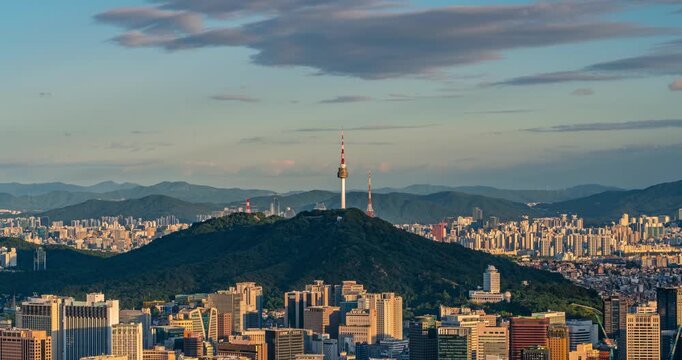 Timelapse captures Namsan Tower rising above a forested peak overlooking downtown Seoul, South Korea skyscrapers glowing in golden afternoon light