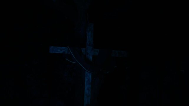 Three wooden crosses lit by strobing lights cycling through colors against total darkness