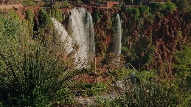 Waterfalls of Ouzoud dropping over red rock cliffs framed by green vegetation Morocco