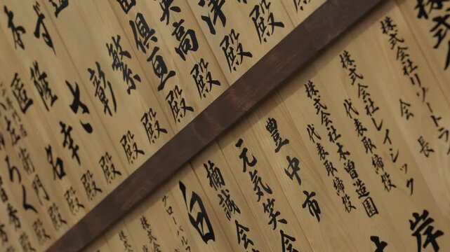 Rows of wooden plaques painted with black kanji calligraphy at a shrine in Japan