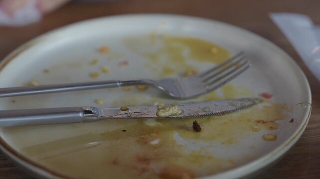 Close up of an empty white plate with knife and fork and leftover food traces