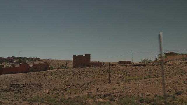 Morocco desert village with date palms and mud brick houses on dry hillside