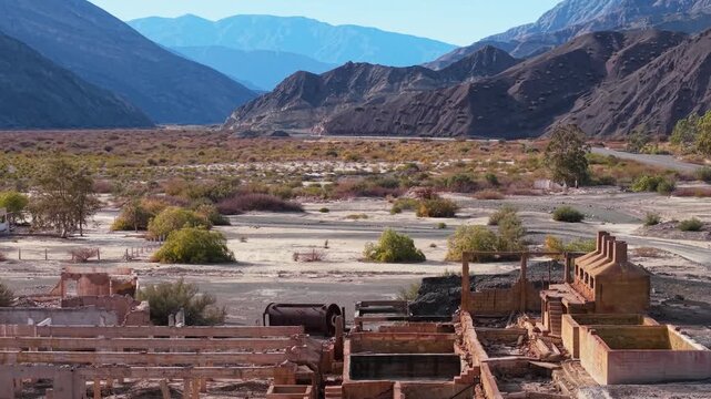 Aluminum sulfate plant ruins in Calingasta, San Juan, Argentina below rugged mountains, drone overview of structural remnants