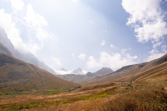 Mountain landscape with clouds and meadows.