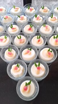 Vertical zoom out reveal of Asian milk pudding desserts with lychee and pandan in glass bowls for catering banquet