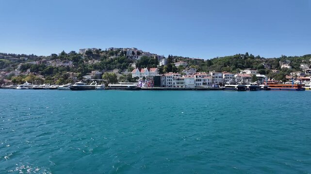 Waterfront view from the water toward historic yalı mansions, hillside homes and boats docked along the Bosphorus Strait shoreline in Bebek, Istanbul, Turkey