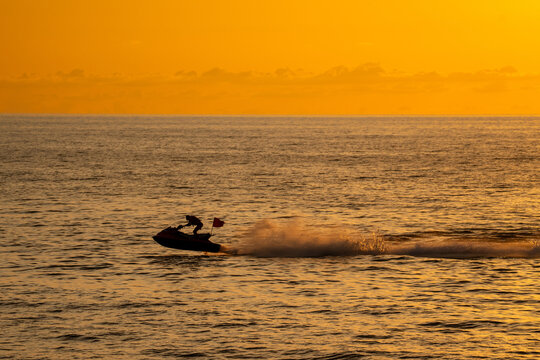 A man on a jet ski at sunset