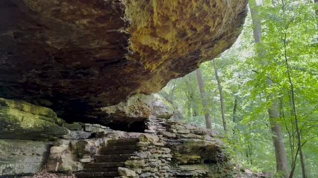 Panning views following a stone hiking path up to massive rock formations in lush forest at Bell Smith Springs in Shawnee National Forest, Southern Illinois.