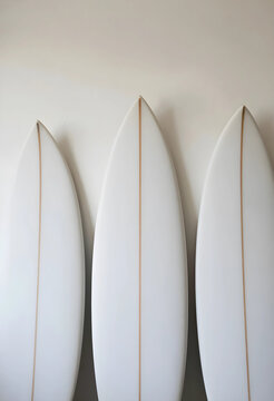 Surf culture and beach lifestyle, three white surfboards with wooden stringers leaning against a wall, summer sports equipment