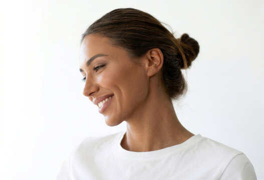 Side view profile of a smiling woman with hair bun in a white t-shirt.