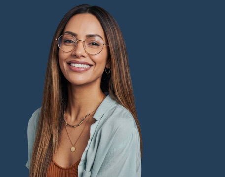 Portrait of a smiling woman with glasses and long hair against dark blue background.