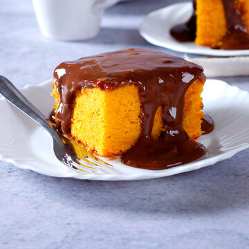 Brazilian carrot cake with a soft crumb, topped with creamy chocolate, on a white plate