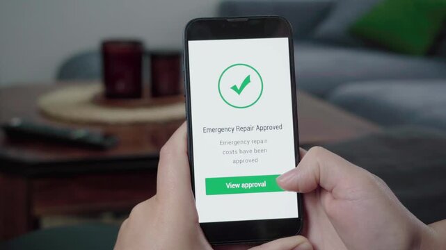 Hands operate a mobile phone showing an emergency repair costs approved message with a large check icon and view approval button.