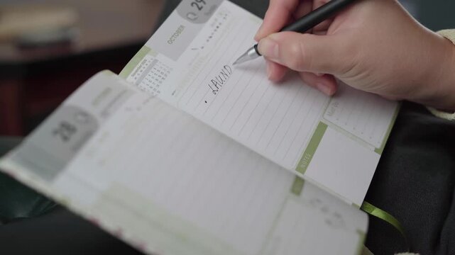Close-up of a person adding laundry and house cleaning tasks to a lined daily planner page, emphasizing home chore organization.