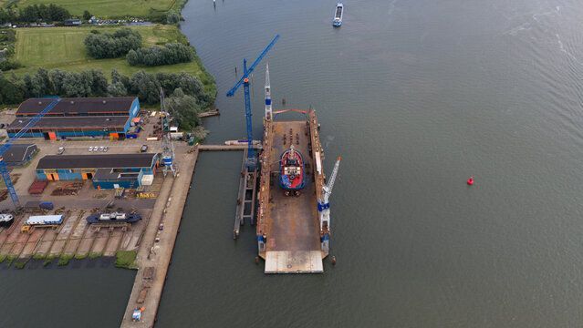 Amsterdam, Netherlands - 03 July 2026: Aerial view of Damen Shiprepair Oranjewerf with a tugboat in a floating dry dock, surrounded by shipyard facilities, cranes, and the IJ river.